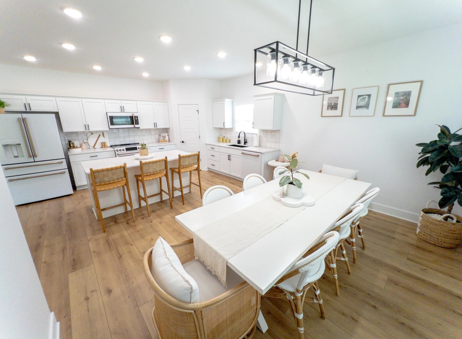 White kitchen cabinetry, a central island and dining space with wood flooring