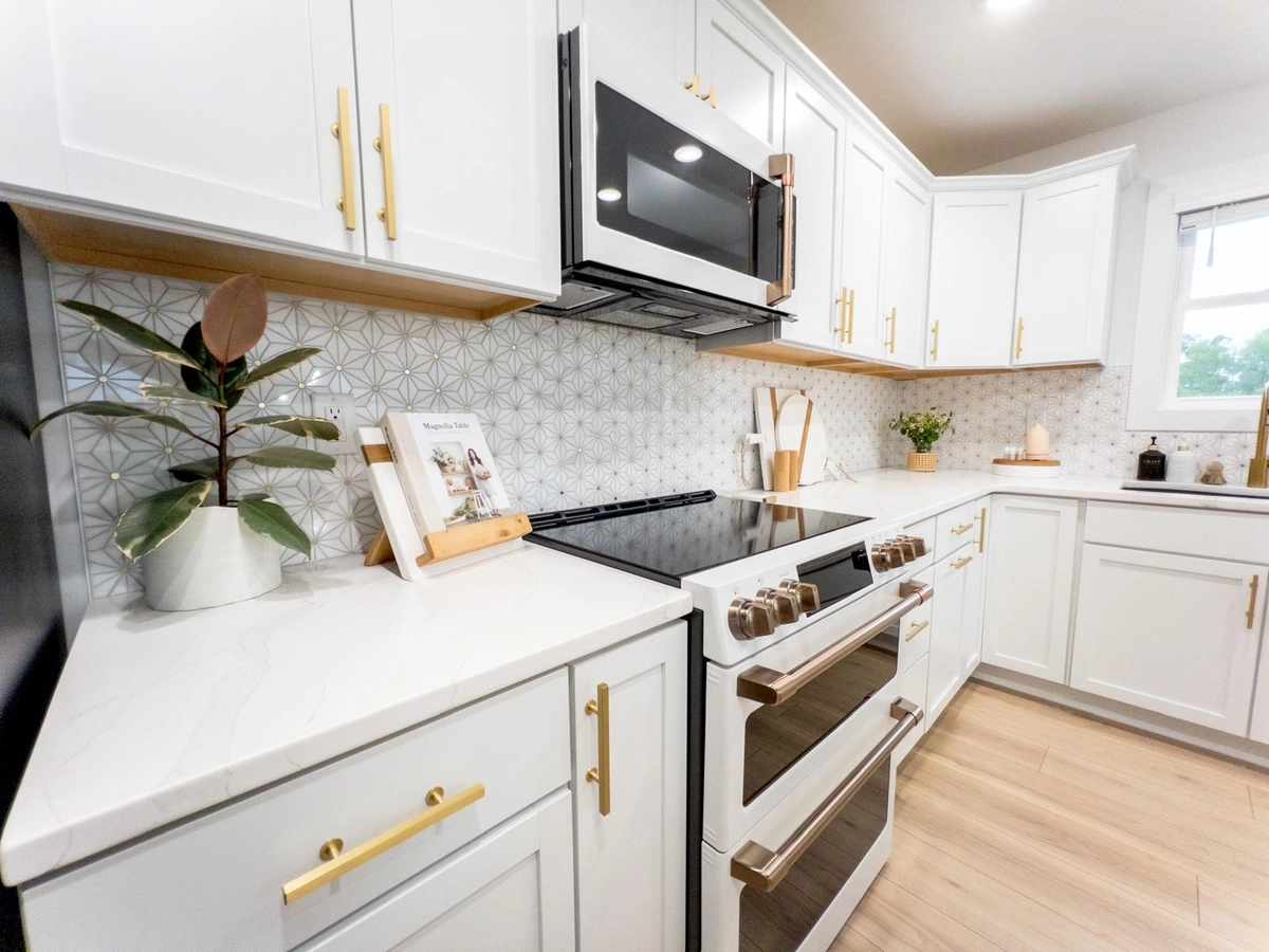 Range, white cabinets and patterned tile backsplash