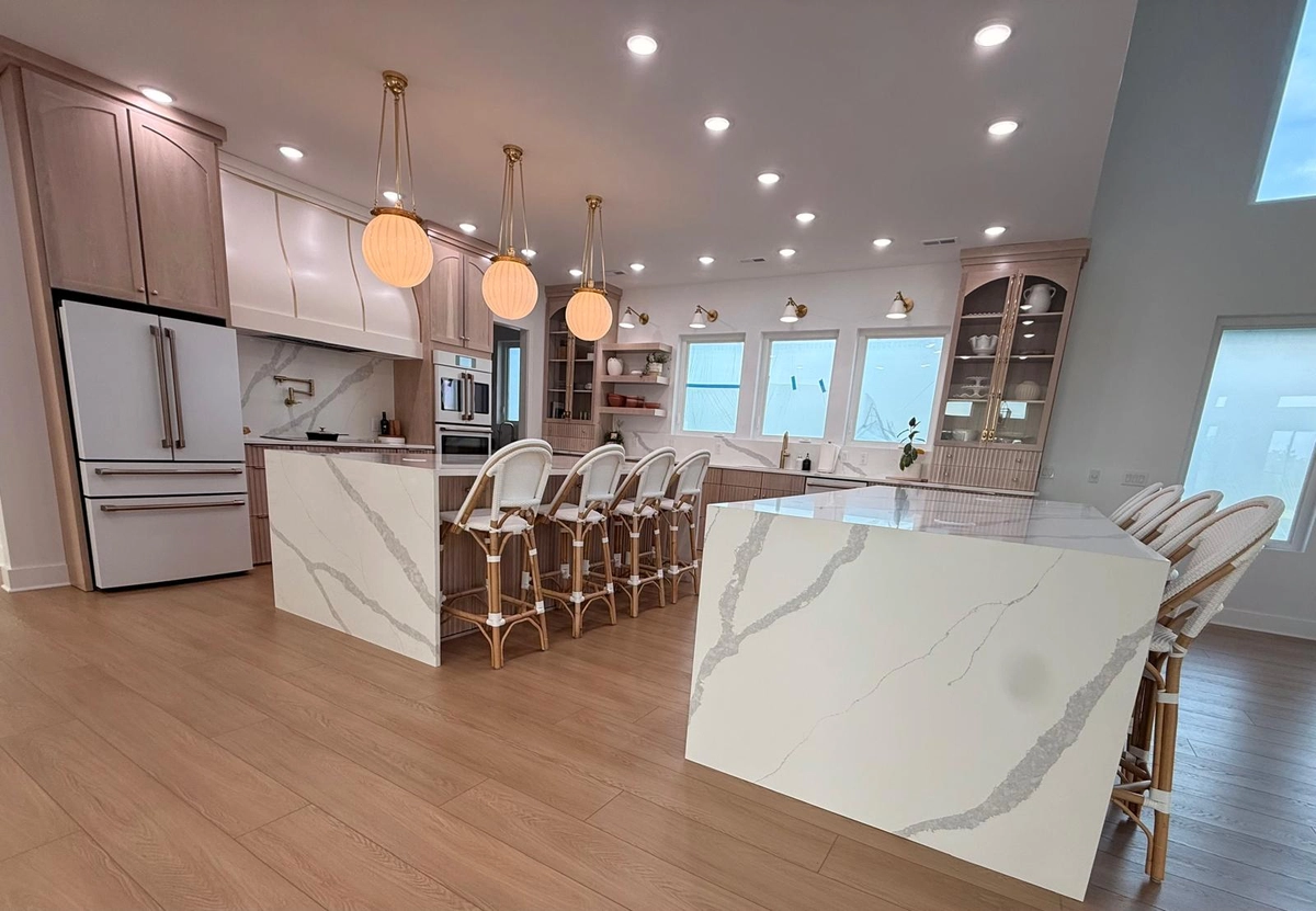 Pale veined island countertop, pendant lighting and seating