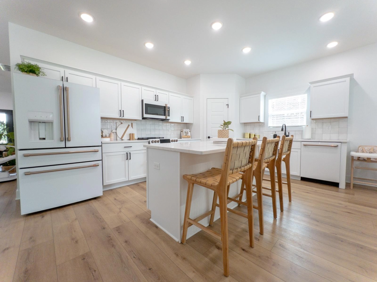 White cabinetry and a central island with seating in the completed kitchen