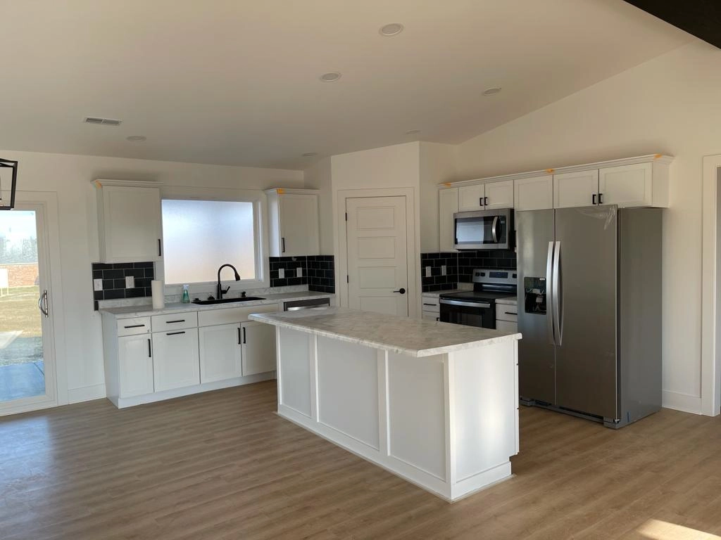 White kitchen with a central island and connected living space at 8215 Salem Church Road