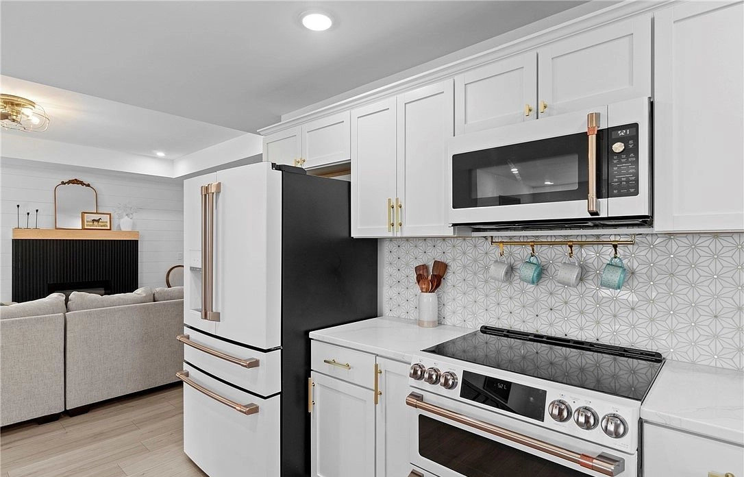 White kitchen cabinets with brass-colored handles, stainless appliances and a patterned backsplash at 8215 Salem Church Road