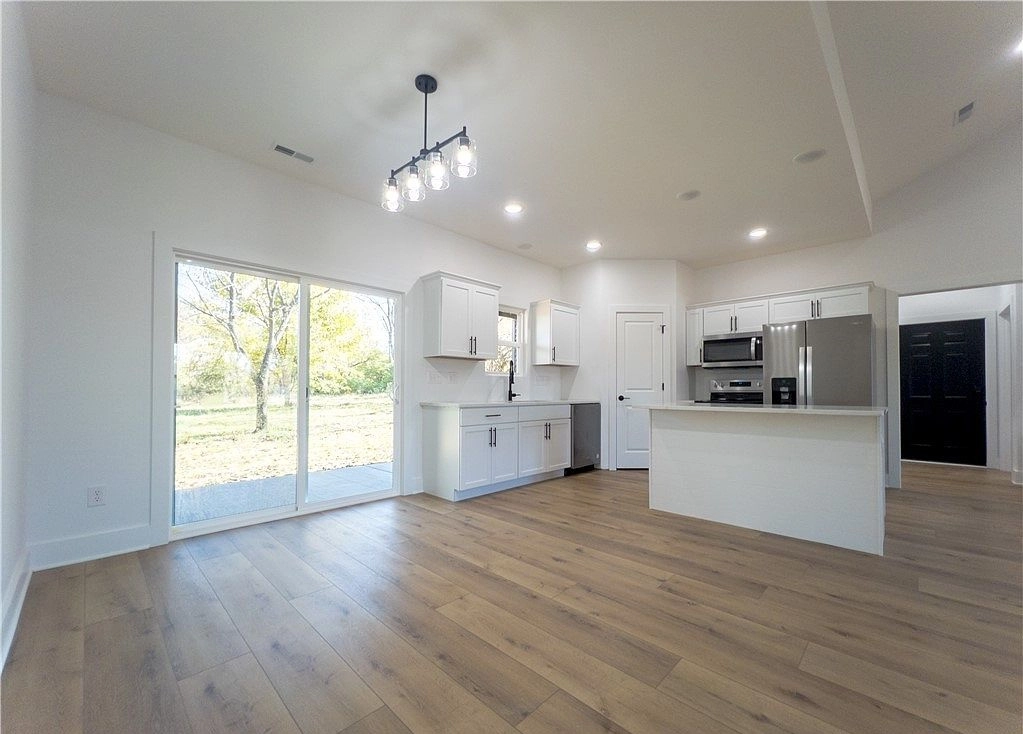 White kitchen with an island, stainless appliances and a rear glazed door