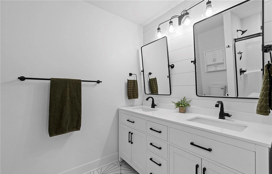 Bathroom double vanity with black fixtures, two rectangular mirrors and white cabinetry at 8215 Salem Church Road