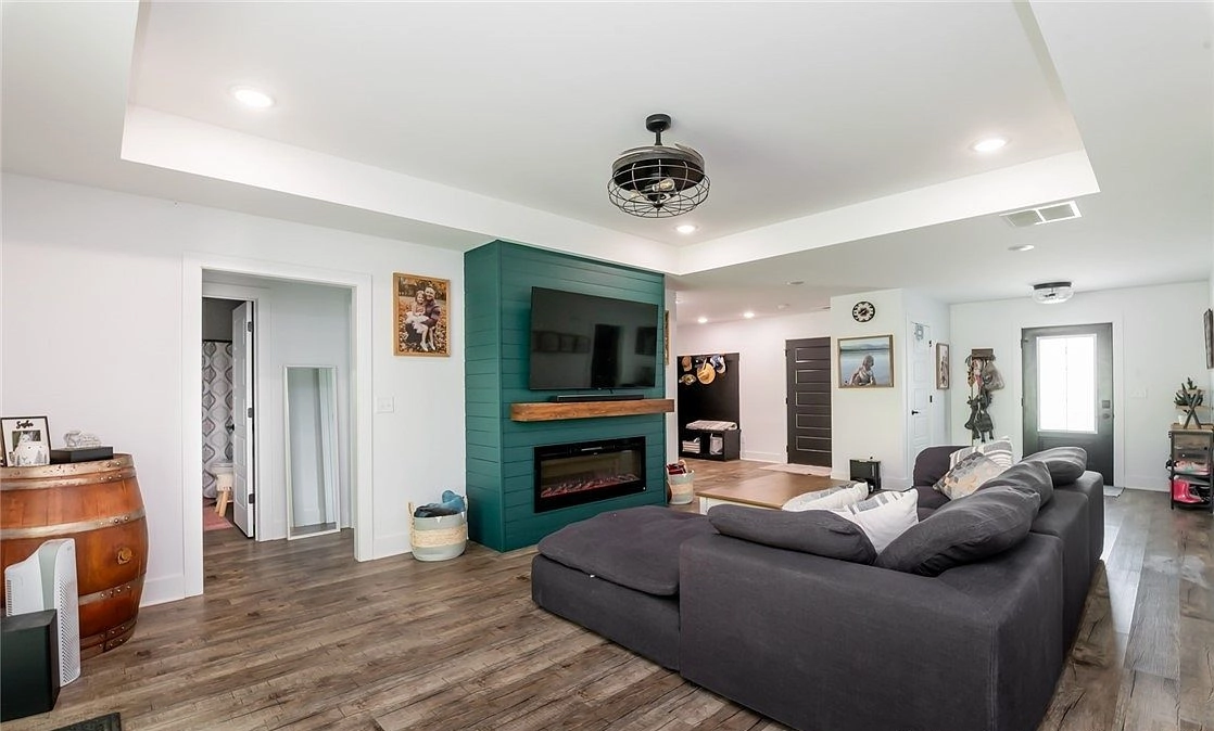 Living room with a tray ceiling, sectional sofa and green paneled fireplace surround