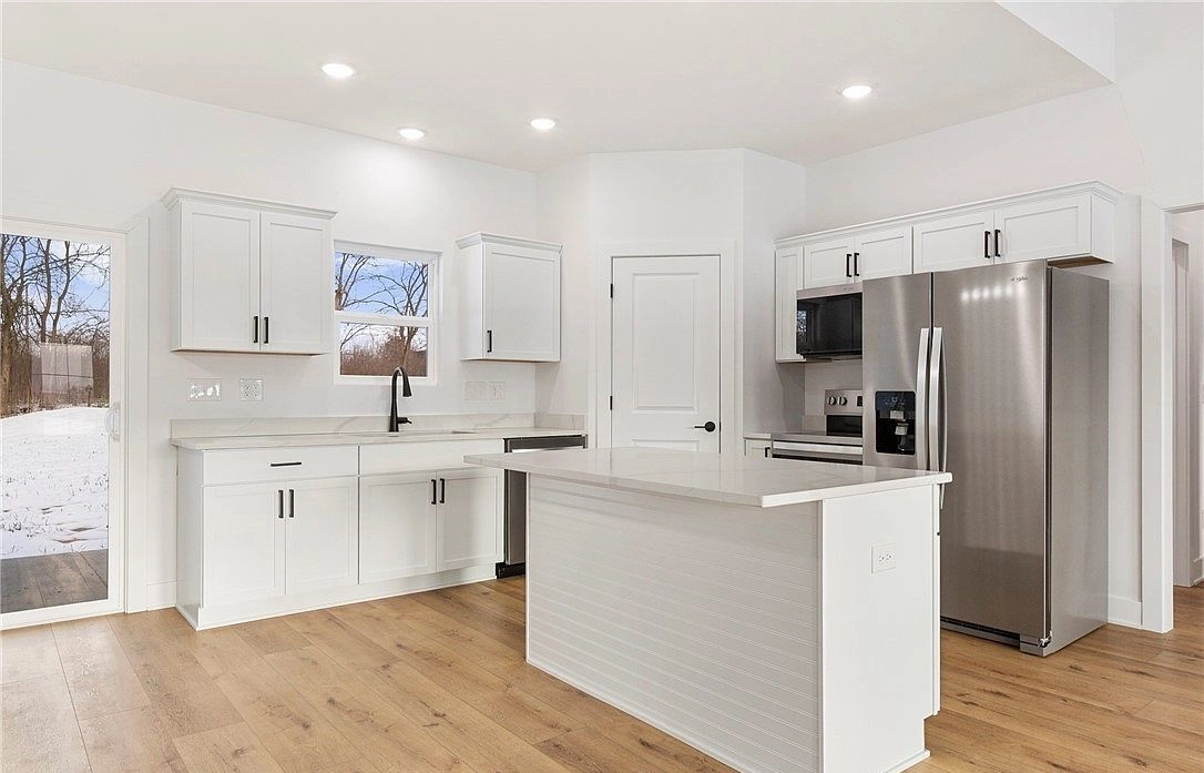 White kitchen with a central island, stainless appliances and a herringbone backsplash at 5608 High Jackson Road