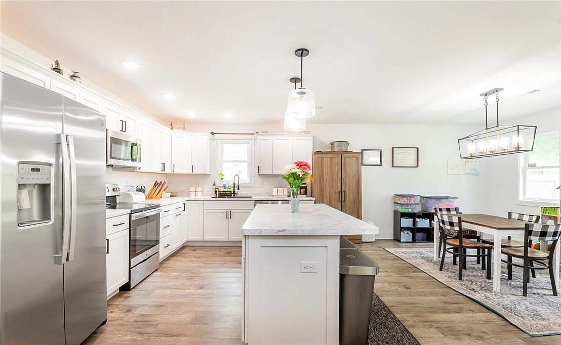 View along the kitchen island toward a dining table and windows